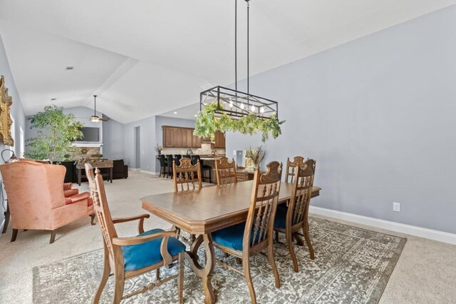 carpeted dining room featuring ceiling fan with notable chandelier and vaulted ceiling