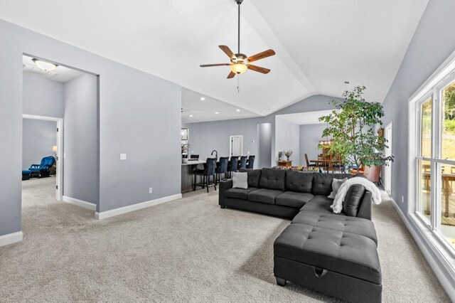 living room with lofted ceiling, ceiling fan, and light colored carpet