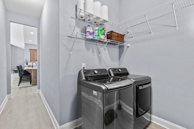 washroom with separate washer and dryer and light hardwood / wood-style flooring