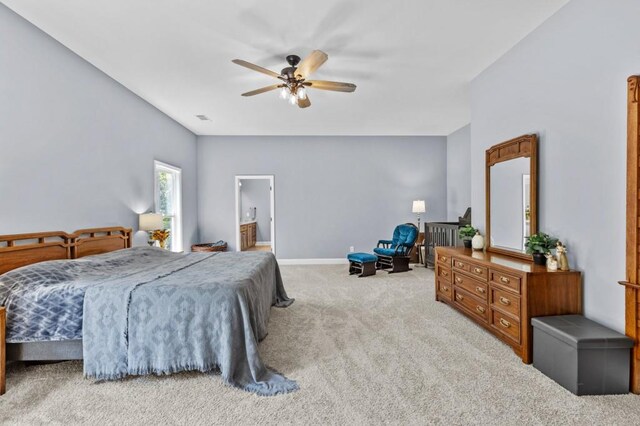 carpeted bedroom with ensuite bath and ceiling fan