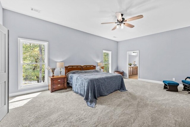 bedroom featuring ensuite bath, ceiling fan, and light colored carpet