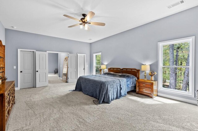 bedroom featuring multiple windows, light colored carpet, and ceiling fan