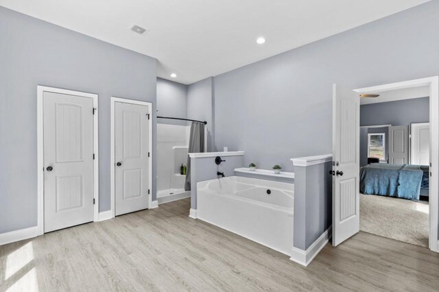 bathroom featuring hardwood / wood-style flooring and separate shower and tub