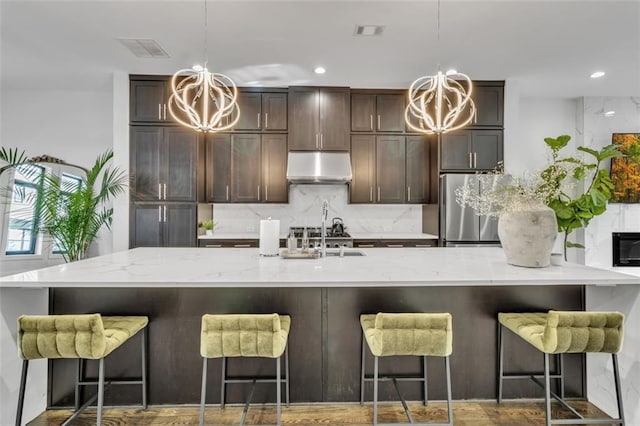 kitchen featuring pendant lighting, a breakfast bar area, stainless steel refrigerator, tasteful backsplash, and a chandelier