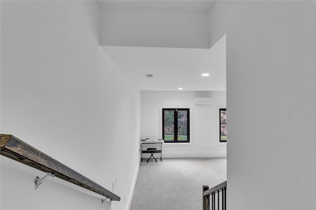 corridor featuring light colored carpet and a wall mounted AC