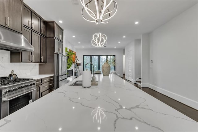 kitchen featuring hanging light fixtures, stainless steel appliances, light stone countertops, decorative backsplash, and a chandelier