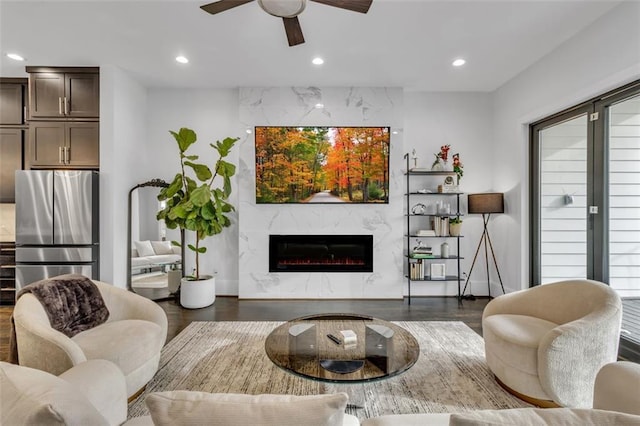 living room with dark hardwood / wood-style floors, ceiling fan, and a premium fireplace