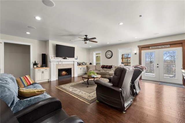 living room featuring ceiling fan, a fireplace, dark wood-type flooring, and french doors