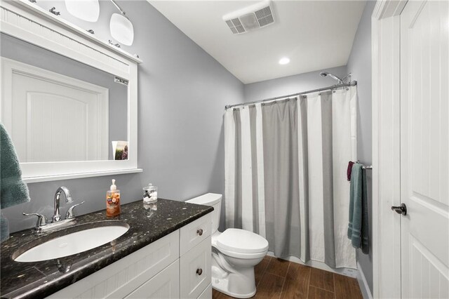 bathroom featuring hardwood / wood-style floors, vanity, toilet, and walk in shower