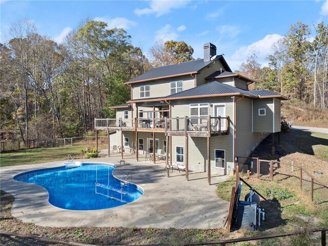 rear view of property featuring a pool side deck and a patio