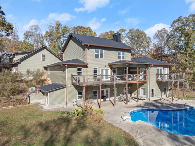 back of property featuring a pool side deck and a patio