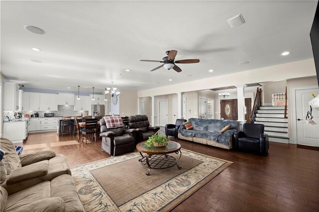 living room featuring ornate columns, wood-type flooring, and ceiling fan with notable chandelier