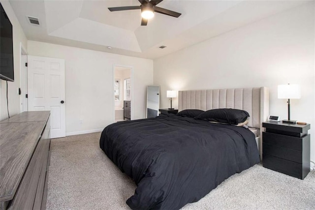 carpeted bedroom with ceiling fan, ensuite bath, and a tray ceiling