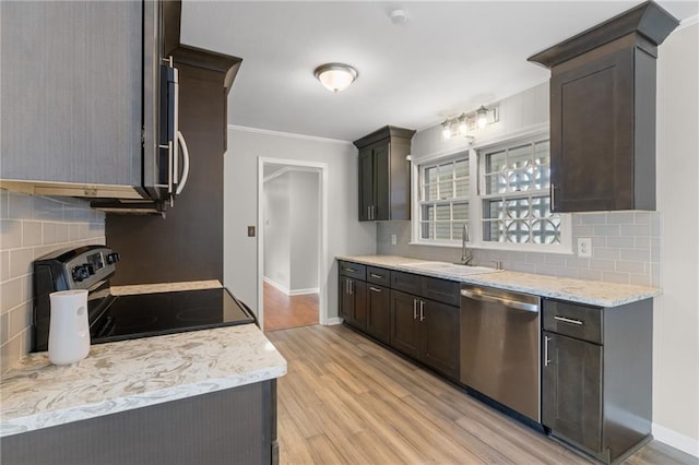 kitchen with light wood-style flooring, appliances with stainless steel finishes, ornamental molding, a sink, and dark brown cabinets