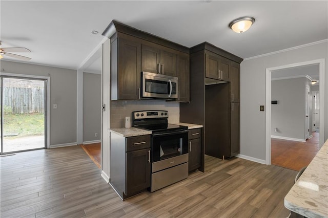 kitchen with crown molding, decorative backsplash, appliances with stainless steel finishes, light wood-style floors, and dark brown cabinetry