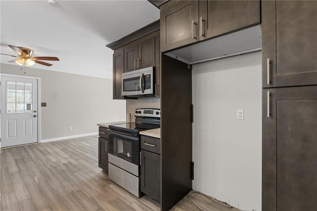 kitchen with appliances with stainless steel finishes, a ceiling fan, dark brown cabinetry, light wood-type flooring, and baseboards