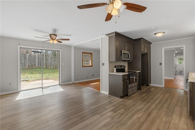 kitchen featuring light countertops, light wood-style flooring, appliances with stainless steel finishes, ornamental molding, and dark brown cabinets