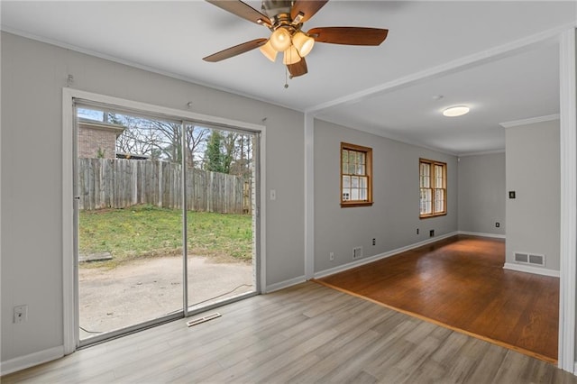 interior space with ornamental molding, wood finished floors, visible vents, and baseboards