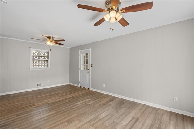 empty room with visible vents, ceiling fan, baseboards, and wood finished floors