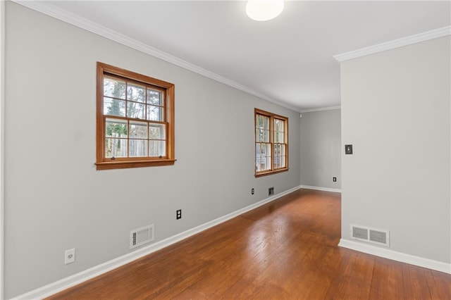 empty room featuring a wealth of natural light, wood finished floors, and visible vents