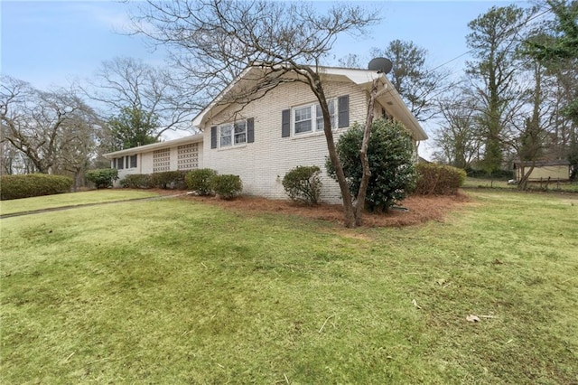 view of side of home with a yard and brick siding