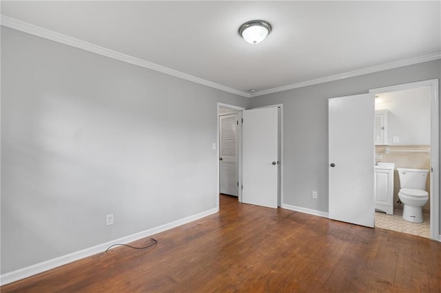 unfurnished bedroom featuring crown molding, wood-type flooring, connected bathroom, and baseboards