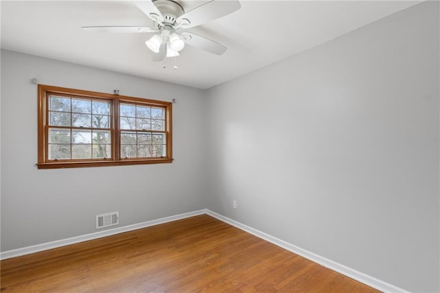 spare room with visible vents, ceiling fan, baseboards, and wood finished floors