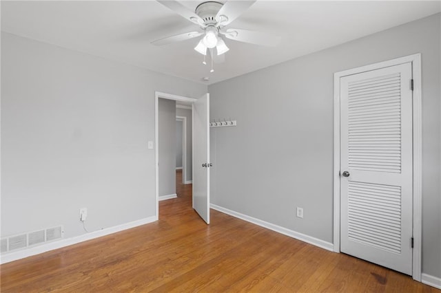 unfurnished bedroom with a closet, visible vents, light wood-style flooring, ceiling fan, and baseboards