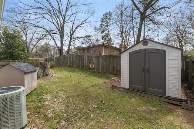 view of yard featuring central air condition unit, a storage shed, a fenced backyard, and an outbuilding