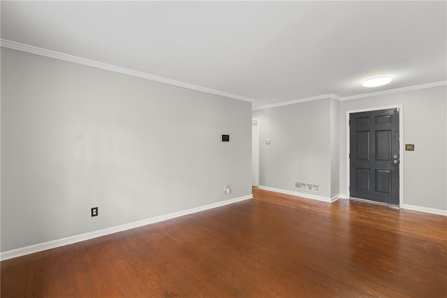 empty room featuring crown molding, wood finished floors, visible vents, and baseboards