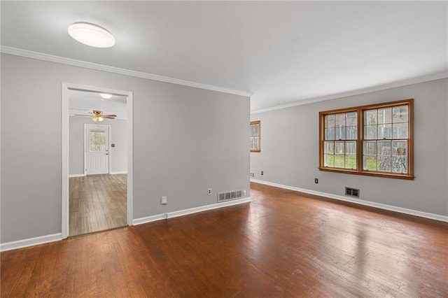 spare room with dark wood-type flooring, plenty of natural light, and visible vents