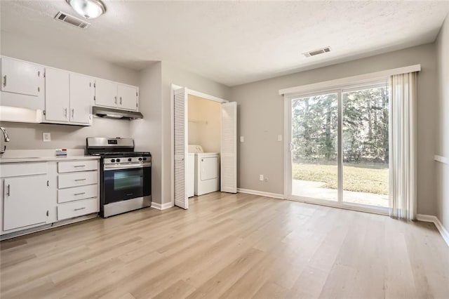 2638 Fieldstone View Ln SE, Conyers, GA 30013 - kitchen with stainless steel gas stove, washer / dryer, under cabinet range hood, light wood-style flooring, and light countertops