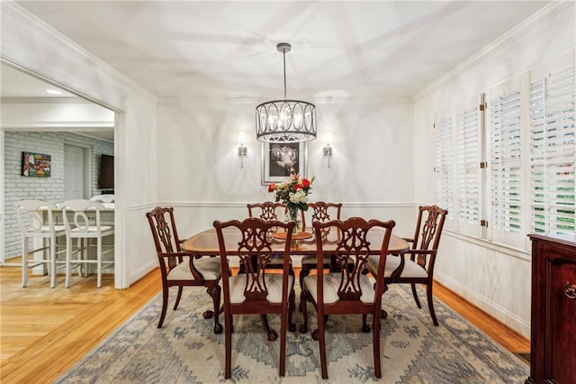 dining area with hardwood / wood-style flooring, ornamental molding, and an inviting chandelier