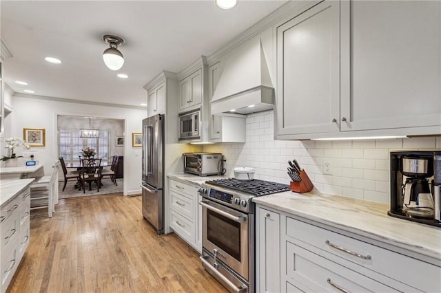 kitchen featuring light stone counters, stainless steel appliances, light hardwood / wood-style floors, and custom exhaust hood