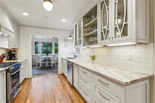 kitchen featuring light stone countertops, appliances with stainless steel finishes, sink, and light wood-type flooring