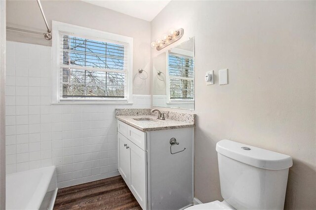 full bathroom with vanity, bathing tub / shower combination, hardwood / wood-style flooring, tile walls, and toilet