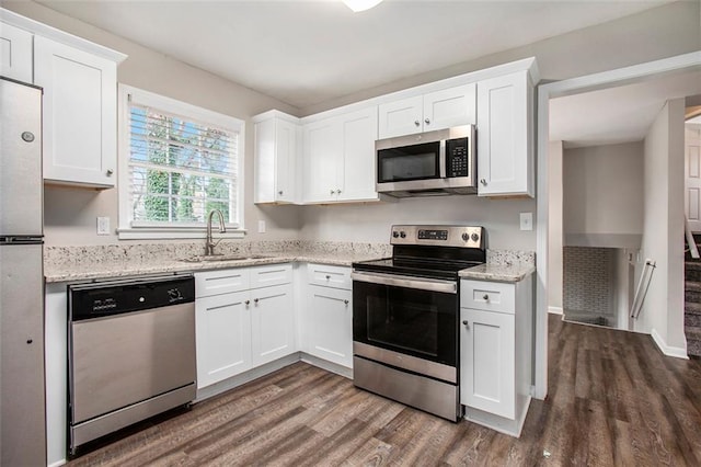 kitchen with light stone countertops, sink, stainless steel appliances, dark hardwood / wood-style floors, and white cabinets