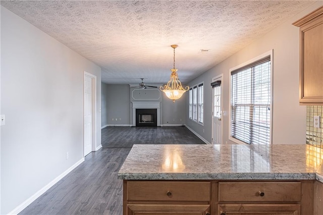1241 Hogan Ridge Ct, Grayson, GA 30017 - kitchen with dark wood-style floors, a peninsula, a fireplace, baseboards, and pendant lighting