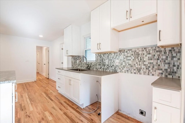 kitchen with white cabinetry, sink, light hardwood / wood-style flooring, and tasteful backsplash