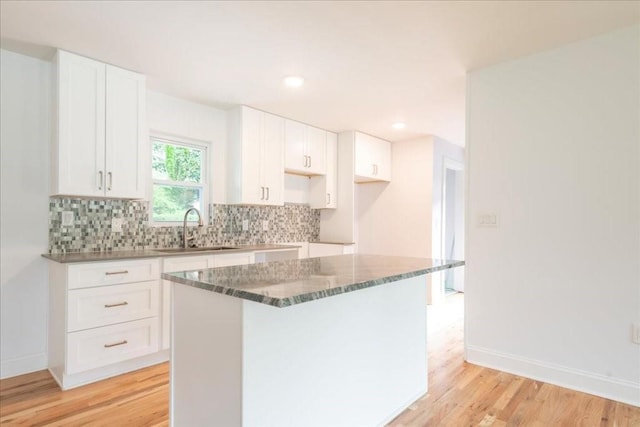 kitchen with a kitchen island, sink, white cabinets, and decorative backsplash