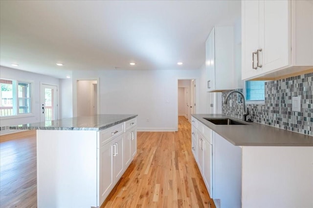 kitchen with sink, a center island, white cabinets, decorative backsplash, and light wood-type flooring