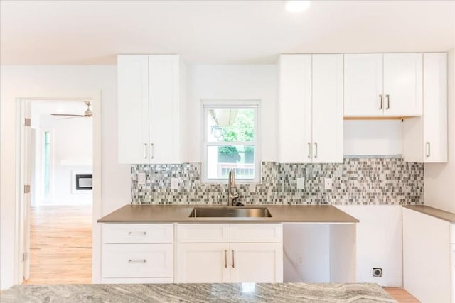 kitchen featuring tasteful backsplash, white cabinetry, sink, and light hardwood / wood-style flooring