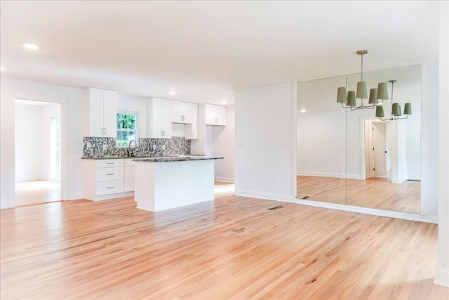 kitchen with decorative light fixtures, a chandelier, white cabinets, and light wood-type flooring