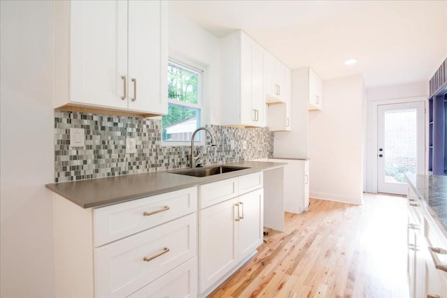 kitchen with sink, backsplash, light hardwood / wood-style flooring, and white cabinets