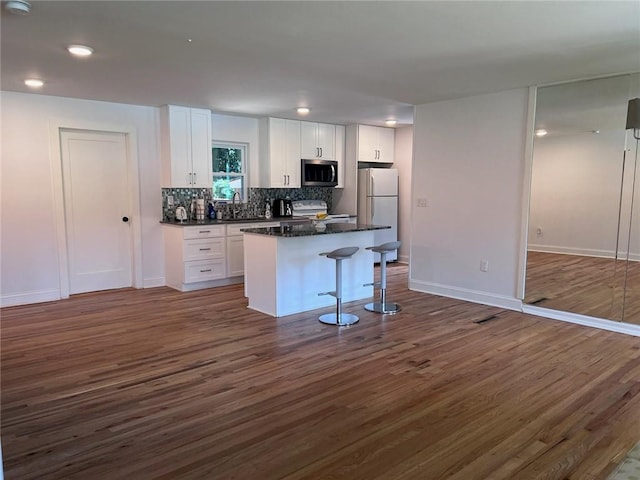 kitchen with appliances with stainless steel finishes, sink, a breakfast bar area, white cabinets, and a center island