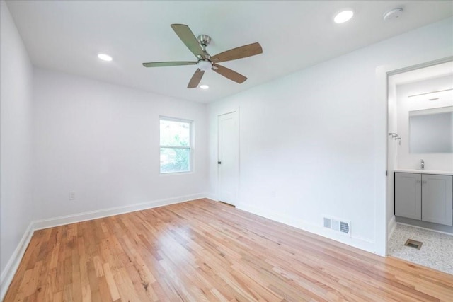 unfurnished bedroom with sink, light hardwood / wood-style flooring, ceiling fan, ensuite bathroom, and a closet