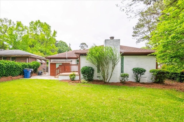 rear view of property featuring a wooden deck and a yard