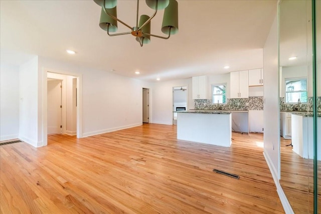 unfurnished living room featuring sink and light hardwood / wood-style flooring