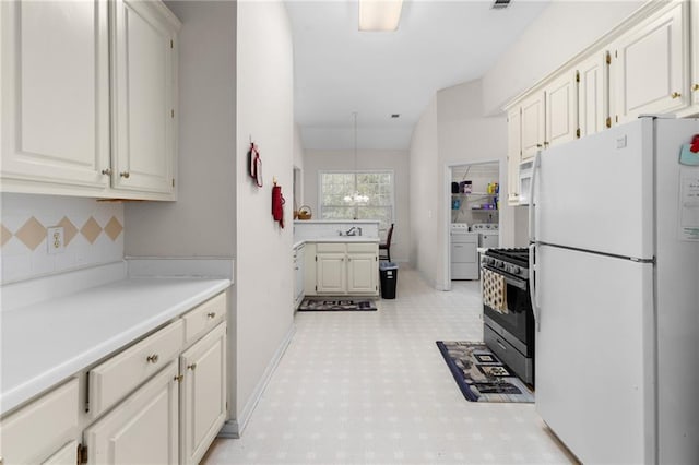 kitchen featuring decorative backsplash, white cabinets, an inviting chandelier, separate washer and dryer, and white appliances