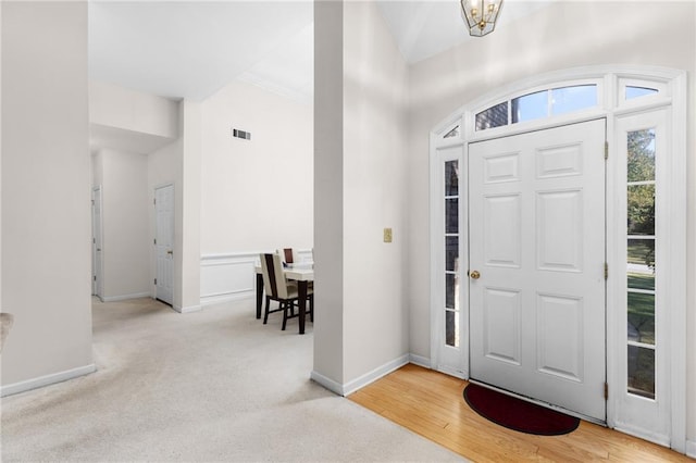 entryway with ornamental molding, light hardwood / wood-style flooring, and a notable chandelier